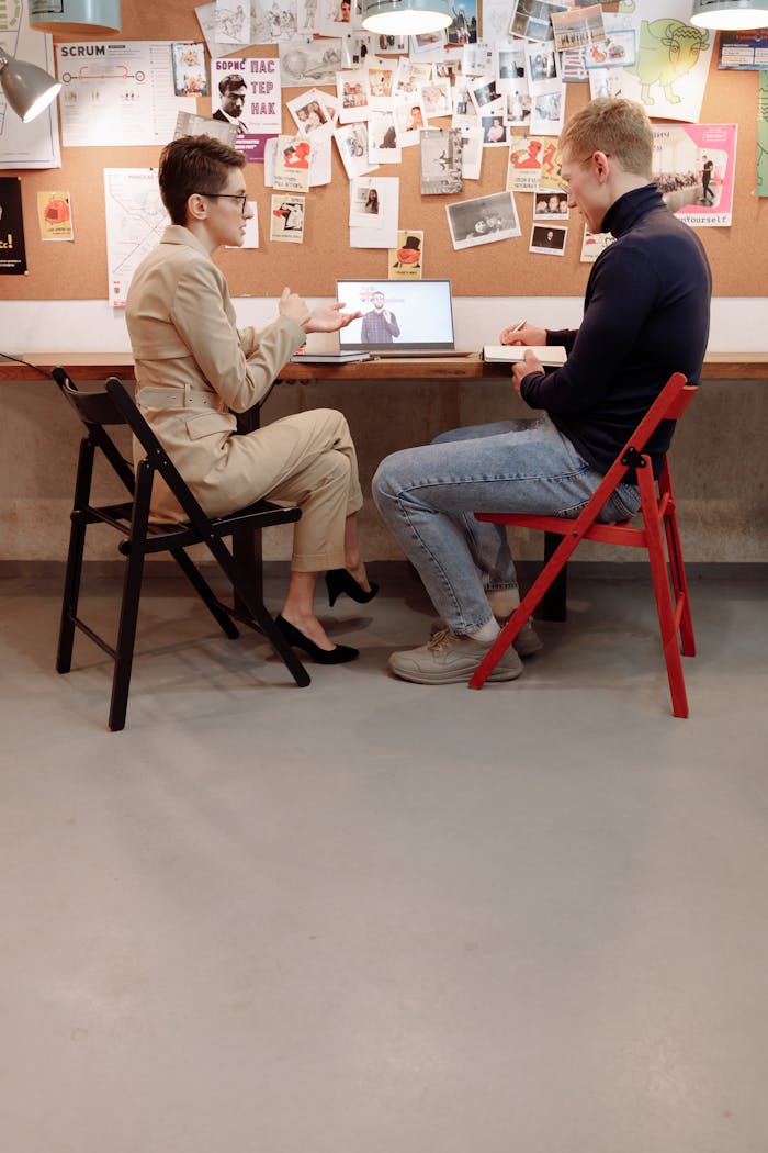 Two adults in a brainstorming session with a laptop in an office.
